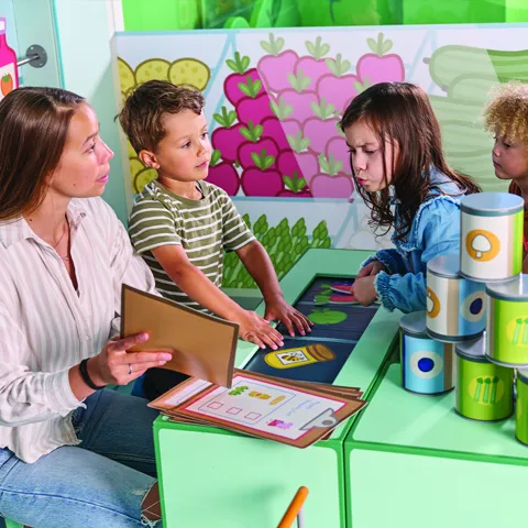 An adult teaching 3 children at PEPPA PIG World of Play